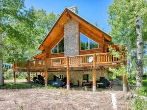 Front of property featuring log exterior, stone fireplace, and a wooden deck