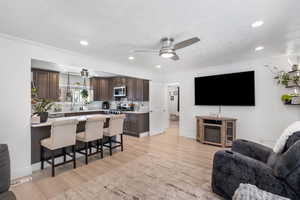 Living room with ornamental molding, a ceiling fan, visible vents, recessed lighting, and light wood finished floors