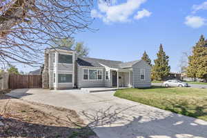 View of front of property featuring a shingled roof, driveway, fence, and a front lawn