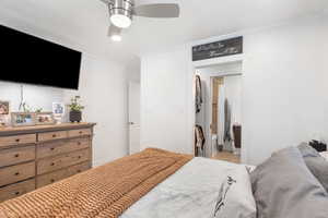 Bedroom with ensuite bath, baseboards, ornamental molding, and ceiling fan