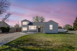 View of front of property with concrete driveway, fence, and a lawn