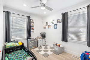 Bedroom featuring baseboards, multiple windows, and wood finished floors