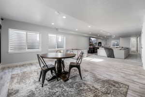 Dining room with light wood-style flooring, recessed lighting, baseboards, and a textured ceiling