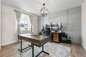 Office with a chandelier, a decorative wall, light wood-style flooring, and baseboards