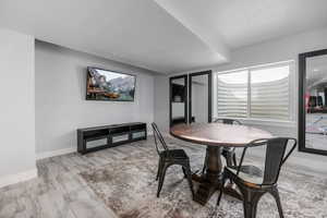 Dining room with baseboards, a textured ceiling, and wood finished floors