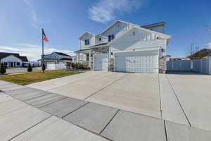 View of front of home with driveway, board and batten siding, stone siding, and an attached garage
