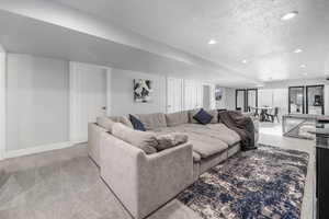 Living room with light carpet, recessed lighting, a textured ceiling, and baseboards