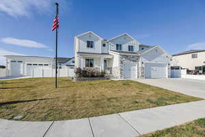 Traditional-style home featuring driveway, board and batten siding, stone siding, a front yard, and fence
