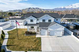 View of front of house with a front yard, a shingled roof, stone siding, board and batten siding, and fence