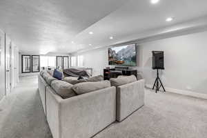 Living room featuring a textured ceiling, baseboards, light carpet, and recessed lighting