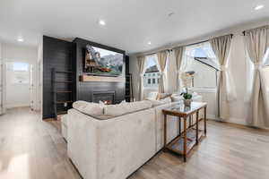 Living area featuring recessed lighting, a fireplace, light wood finished floors, and baseboards