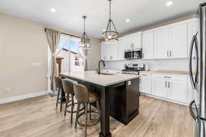 Kitchen with tasteful backsplash, baseboards, a chandelier, appliances with stainless steel finishes, and a sink