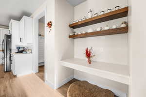 Interior space with light wood finished floors, freestanding refrigerator, and baseboards