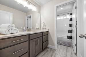 Full bath featuring shower / tub combo with curtain, vanity, wood finished floors, and baseboards