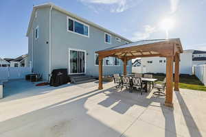 Back of property featuring a patio, outdoor dining area, entry steps, a fenced backyard, and a gazebo
