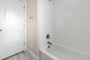 Full bath featuring baseboards, wood finished floors, and shower / washtub combination
