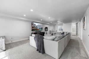 Carpeted living room featuring a textured ceiling, baseboards, and recessed lighting
