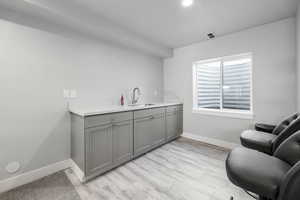 Bar with light wood-style floors, visible vents, recessed lighting, a sink, and baseboards
