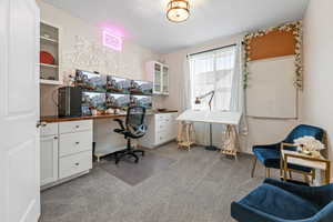 Office space with built in desk and light colored carpet