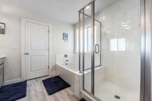 Primary full bath featuring a wealth of natural light, vanity, a garden tub, and a stall shower