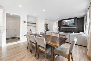 Dining space featuring light wood-style flooring, recessed lighting, a fireplace, and stairway
