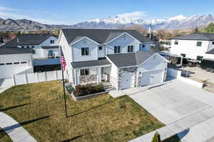 Traditional home featuring concrete driveway, a mountain view, roof with shingles, and fence