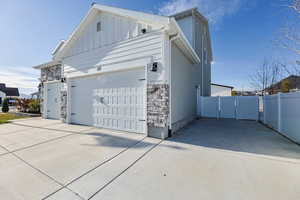 View of home's exterior with concrete driveway, stone siding, an attached garage, and board and batten siding