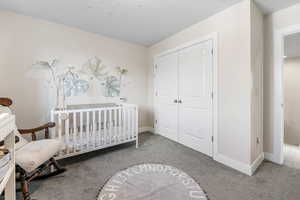 Carpeted bedroom with a closet and baseboards