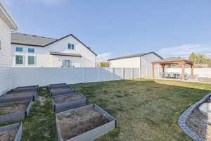 View of yard featuring a gazebo, a patio area, a fenced backyard, and a vegetable garden
