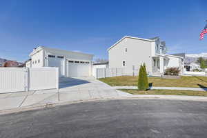 View of front of house featuring board and batten siding, an outdoor structure, fence, a front lawn, and a gate