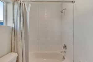 Bathroom with shower / bath combination with curtain and toilet