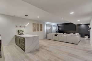 Living room with light wood finished floors, baseboards, visible vents, and recessed lighting