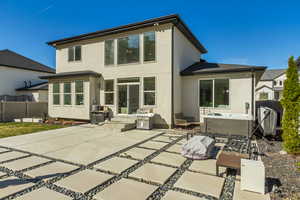 Rear view of house with fence, a patio, stucco siding, and a hot tub