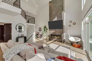 Living area with recessed lighting, a high end fireplace, a towering ceiling, and wood finished floors