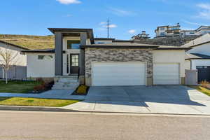View of front facade with an attached garage, concrete driveway, and stucco siding
