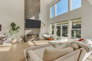 Living area featuring wood finished floors, a high ceiling, and a high end fireplace