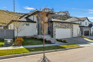 View of front of house featuring stucco siding, a front yard, fence, a garage, and driveway