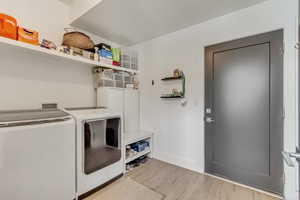 Washroom with baseboards, light wood-style flooring, laundry area, and washing machine and clothes dryer