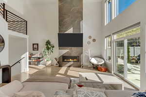 Living room featuring wood finished floors, a towering ceiling, and a fireplace