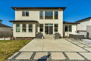 Back of property featuring a hot tub, stucco siding, a lawn, a patio area, and fence