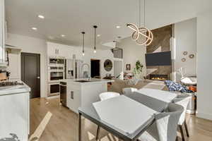 Kitchen with an island with sink, light wood-type flooring, a sink, and appliances with stainless steel finishes
