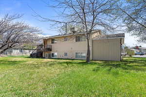 Rear view of property featuring a yard, stairway, central air condition unit, and a chimney