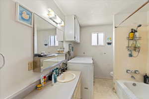 Bathroom with shower / washtub combination, vanity, toilet, washer / dryer, and tile patterned floors