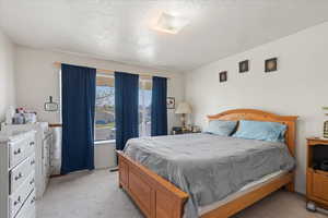 Bedroom with visible vents, light carpet, and a textured ceiling