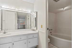 Bathroom featuring toilet, tile patterned floors, vanity, and a tub to relax in