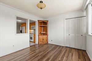 Interior space with a textured ceiling, wood finished floors, and ornamental molding