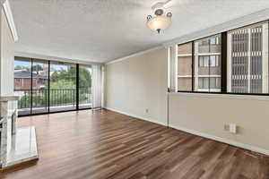 Unfurnished living room featuring ornamental molding, floor to ceiling windows, wood finished floors, and a textured ceiling