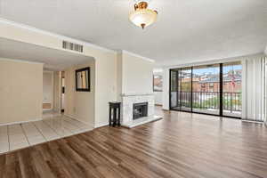 Unfurnished living room featuring visible vents, baseboards, a textured ceiling, wood finished floors, and a premium fireplace