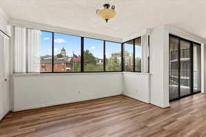 Unfurnished bedroom featuring access to outside, a textured ceiling, wood finished floors, and multiple windows