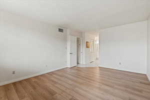Spare room featuring visible vents, baseboards, and light wood-style flooring